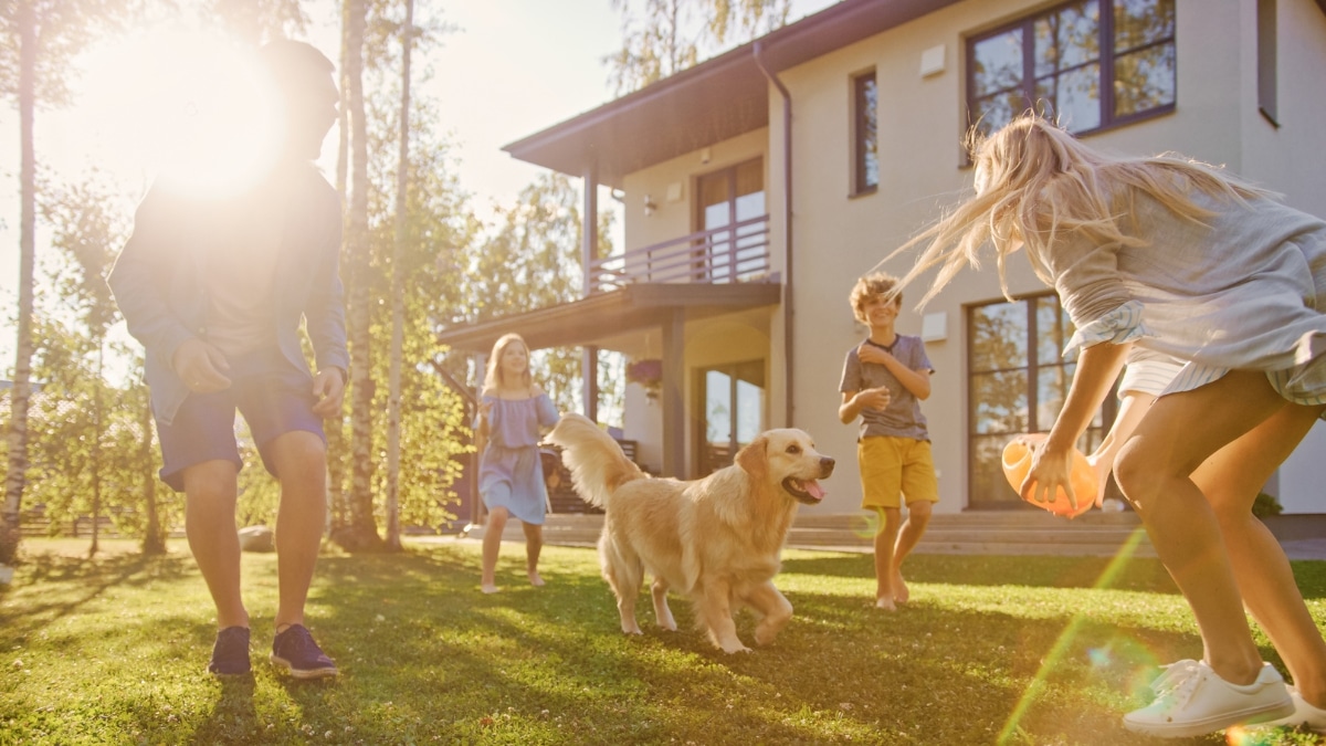 Family playing with their dog outdoors at a well-kept home supported by reliable maid service.